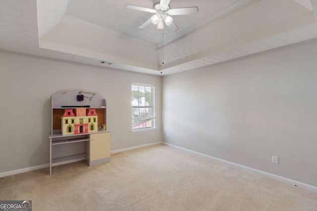 game room featuring a tray ceiling, a textured ceiling, light carpet, ornamental molding, and ceiling fan