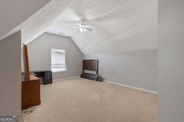 additional living space featuring a textured ceiling, vaulted ceiling, ceiling fan, and light colored carpet