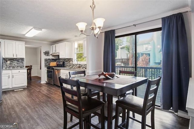 dining room featuring an inviting chandelier, sink, dark wood-type flooring, and a textured ceiling