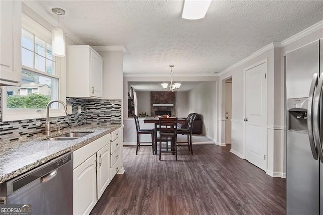 kitchen with stainless steel appliances, white cabinetry, hanging light fixtures, and sink