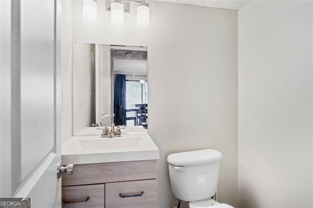 bathroom featuring vanity, a textured ceiling, and toilet