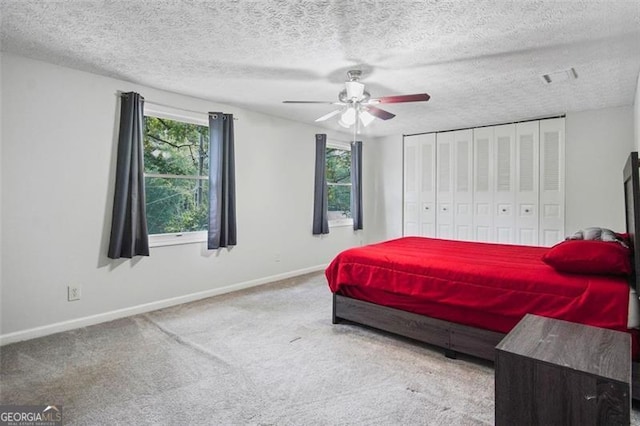 carpeted bedroom with a textured ceiling, ceiling fan, and a closet