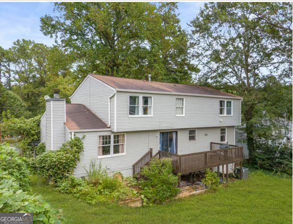 rear view of property featuring a wooden deck, central AC unit, and a lawn