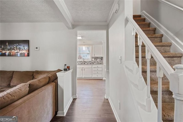 stairs featuring ornamental molding, sink, hardwood / wood-style floors, and a textured ceiling