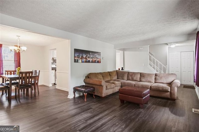 living room featuring dark hardwood / wood-style flooring, a textured ceiling, and a notable chandelier