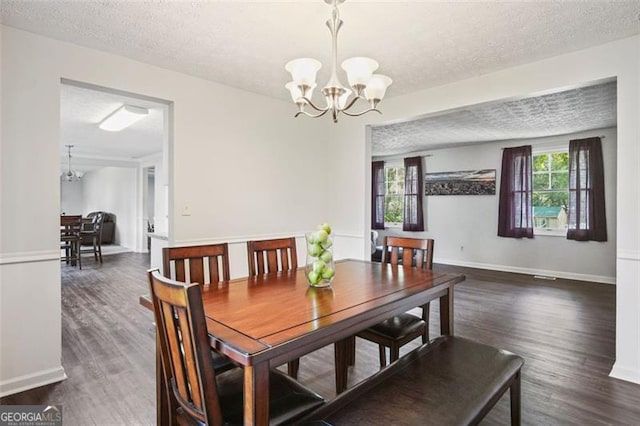 dining area featuring dark hardwood / wood-style floors, a textured ceiling, and a notable chandelier