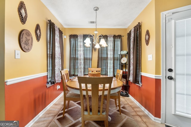 tiled dining area with a textured ceiling and a chandelier