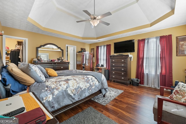 bedroom featuring a closet, dark wood-type flooring, ceiling fan, a raised ceiling, and a spacious closet