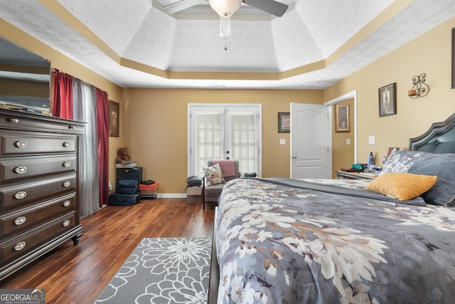 bedroom featuring a raised ceiling, dark hardwood / wood-style flooring, ceiling fan, and a textured ceiling