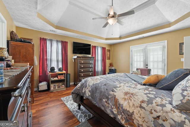 bedroom with ceiling fan, dark hardwood / wood-style floors, a raised ceiling, and a textured ceiling