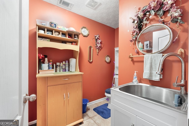 bathroom featuring tile patterned flooring, toilet, a textured ceiling, and sink