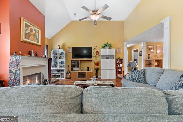 living room featuring high vaulted ceiling, ceiling fan, hardwood / wood-style flooring, and decorative columns