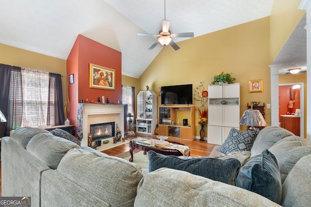 living room with high vaulted ceiling, ceiling fan, and light wood-type flooring