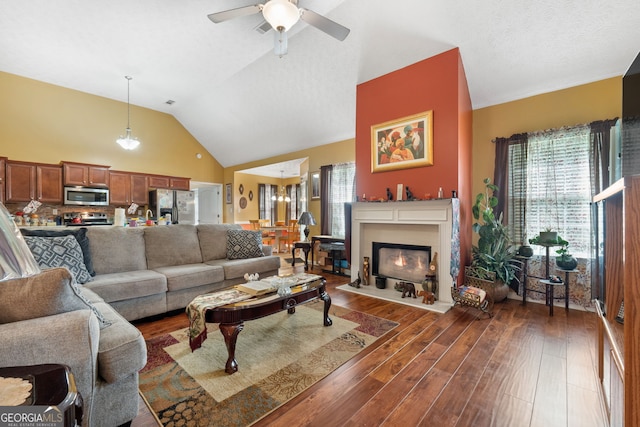 living room with a wealth of natural light, ceiling fan, high vaulted ceiling, and dark hardwood / wood-style flooring