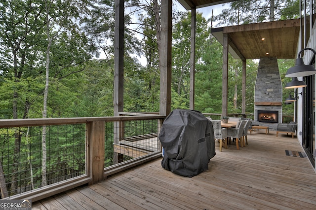 wooden deck featuring area for grilling and an outdoor stone fireplace