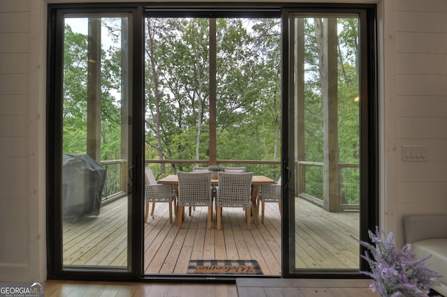 doorway to outside with light hardwood / wood-style floors, wooden walls, and a wealth of natural light