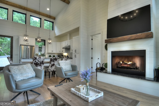 living room with beamed ceiling, a towering ceiling, and light hardwood / wood-style floors