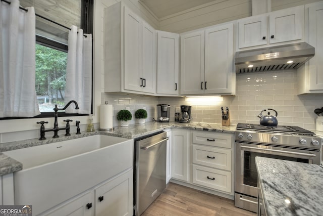 kitchen featuring light stone countertops, white cabinetry, light hardwood / wood-style floors, and appliances with stainless steel finishes