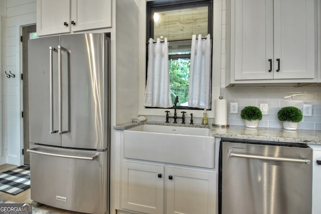 kitchen featuring light stone counters, white cabinets, appliances with stainless steel finishes, and sink