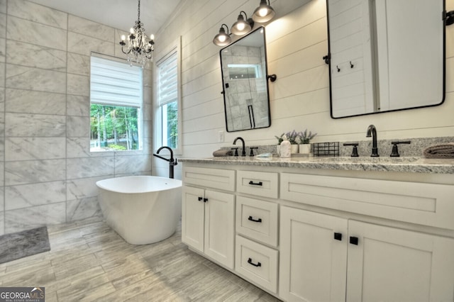 bathroom with a notable chandelier, tile walls, vanity, and a bathtub