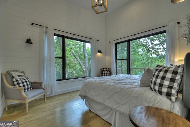 bedroom with multiple windows, a towering ceiling, and light hardwood / wood-style flooring