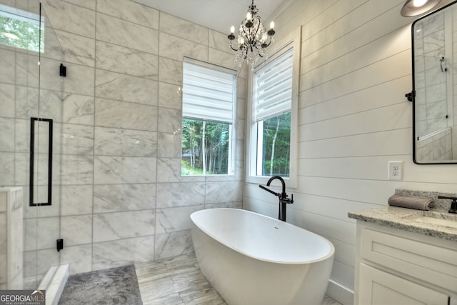 bathroom with a notable chandelier, vanity, and separate shower and tub