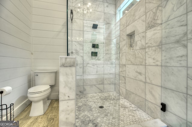 bathroom with tiled shower, toilet, and hardwood / wood-style flooring