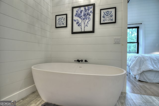 bathroom featuring wood-type flooring, wood walls, and a tub