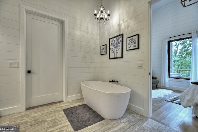 bathroom featuring an inviting chandelier, wood-type flooring, and a bathing tub