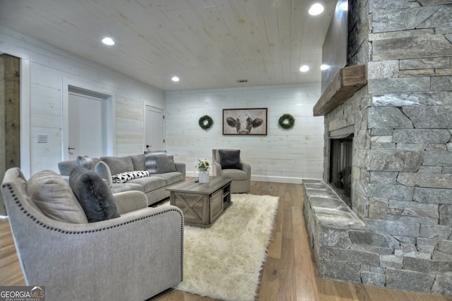 living room featuring a stone fireplace, wood walls, and hardwood / wood-style floors