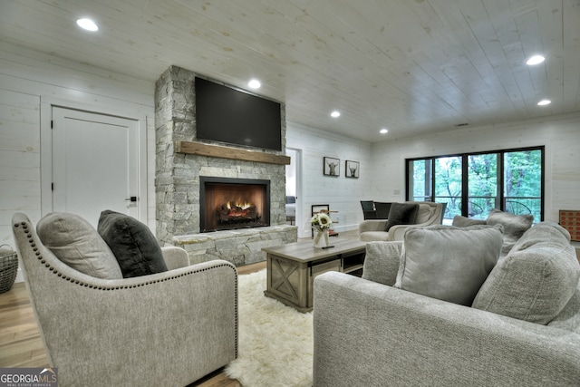 living room with light hardwood / wood-style floors, a fireplace, wood walls, and wood ceiling