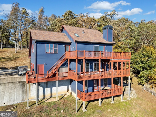 back of house with a wooden deck and a lawn