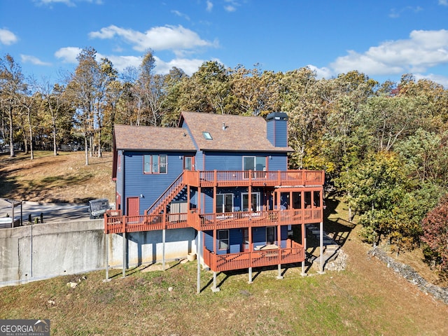 back of property featuring a wooden deck and a yard