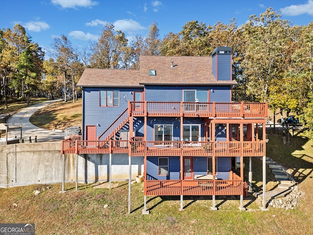 back of property featuring a wooden deck and a lawn