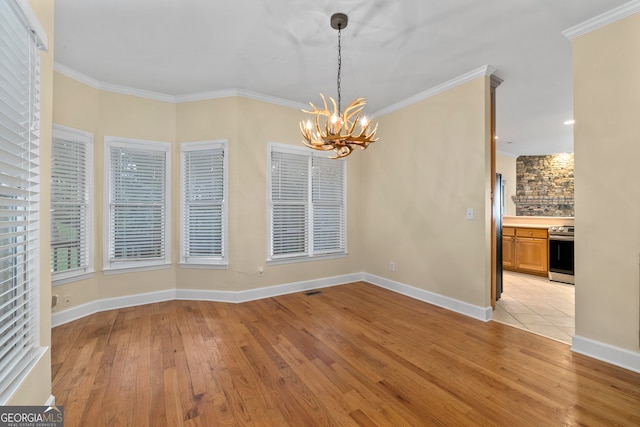 unfurnished dining area with ornamental molding, light hardwood / wood-style flooring, and a chandelier