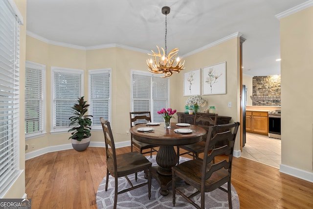 dining room with a notable chandelier, ornamental molding, and light wood-type flooring