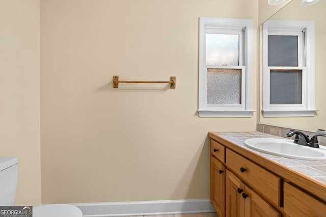 bathroom with toilet, vanity, and tile patterned floors