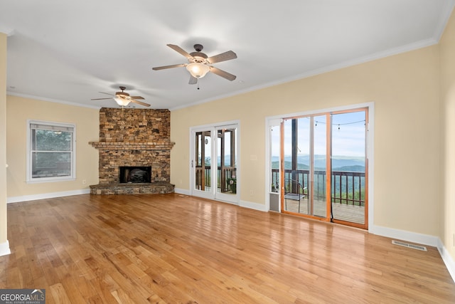 unfurnished living room with light hardwood / wood-style flooring, a mountain view, a healthy amount of sunlight, and crown molding