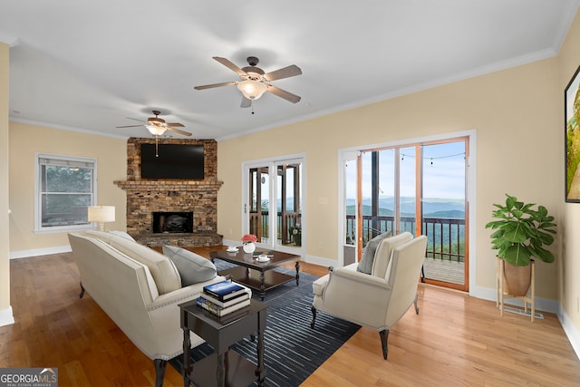 living room featuring crown molding, light hardwood / wood-style flooring, a fireplace, and ceiling fan