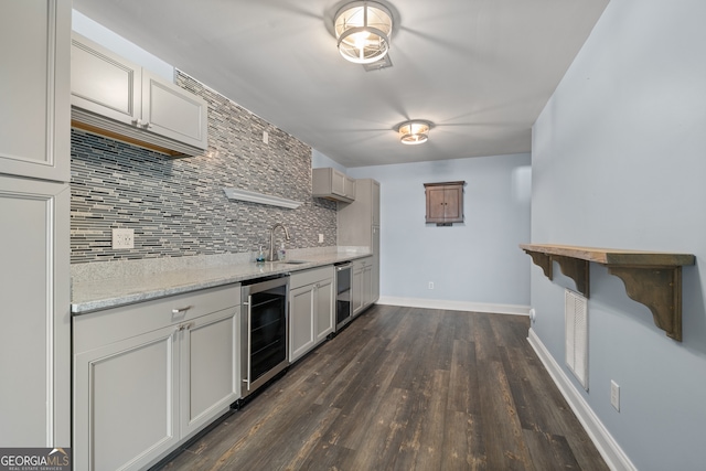 kitchen with decorative backsplash, wine cooler, dark hardwood / wood-style flooring, light stone countertops, and sink