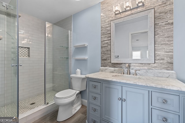 bathroom featuring hardwood / wood-style floors, walk in shower, tile walls, toilet, and vanity