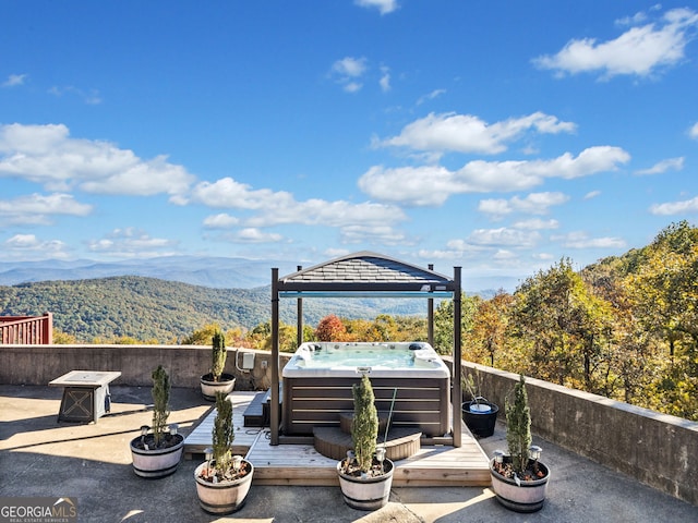 view of patio featuring a hot tub, a mountain view, and a gazebo