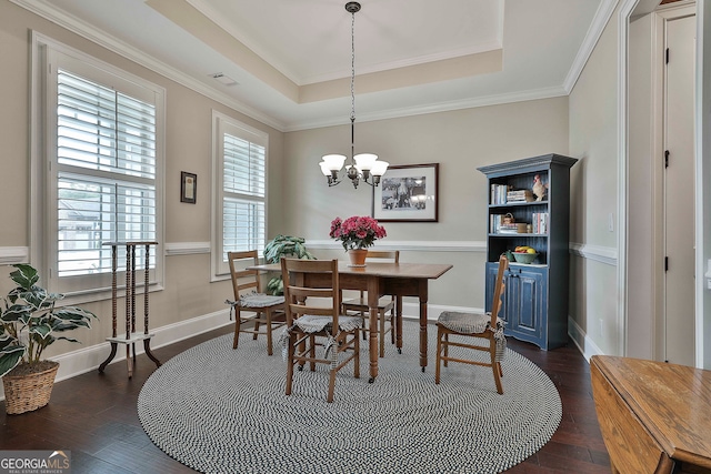 dining room featuring a notable chandelier, a tray ceiling, dark hardwood / wood-style floors, and crown molding