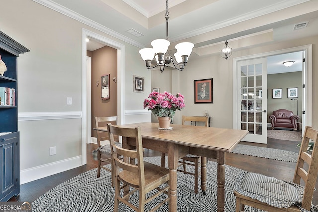 dining room featuring ornamental molding, a tray ceiling, an inviting chandelier, and dark hardwood / wood-style flooring