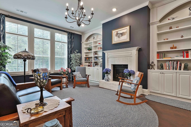 living room featuring built in features, ornamental molding, a brick fireplace, dark hardwood / wood-style floors, and a notable chandelier