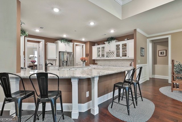 kitchen with a kitchen breakfast bar, white cabinets, dark hardwood / wood-style floors, and stainless steel fridge