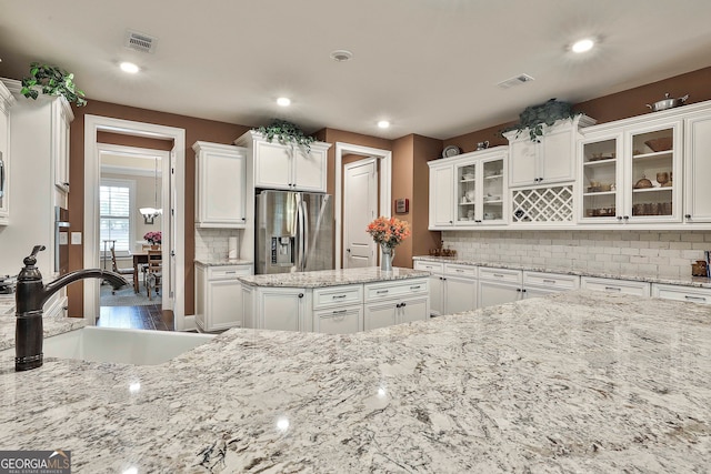 kitchen with decorative backsplash, white cabinetry, sink, and stainless steel fridge with ice dispenser