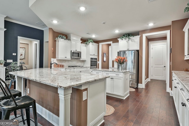 kitchen with a breakfast bar, dark hardwood / wood-style floors, stainless steel appliances, ornamental molding, and a spacious island