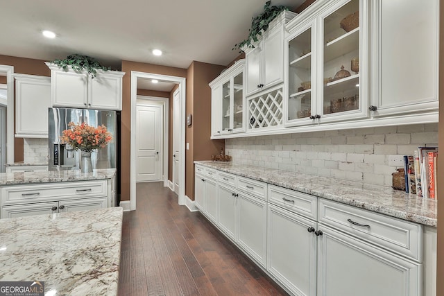 kitchen with white cabinets, light stone counters, dark hardwood / wood-style floors, and backsplash