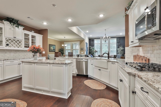 kitchen featuring kitchen peninsula, pendant lighting, stainless steel appliances, an inviting chandelier, and dark hardwood / wood-style floors